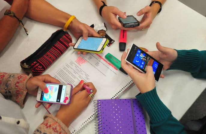 Estudiantes con teléfonos celulares mientras México debate limitar su uso dentro de las escuelas.